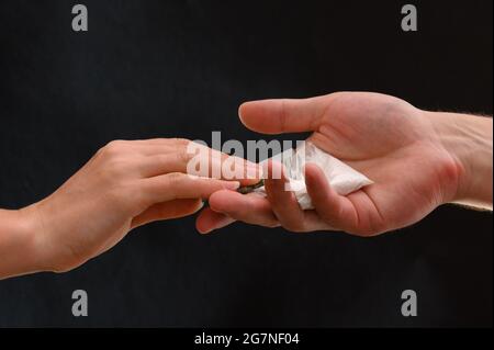 Addict kauft eine Dosis Drogen, weißes Pulver in einem Beutel auf schwarzem Hintergrund. Neu Stockfoto