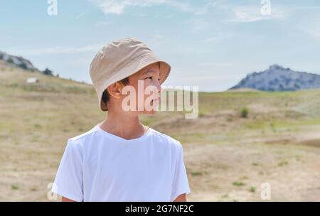Halblanges Porträt eines asiatischen Jungen im weißen T-Shirt, vor dem Hintergrund der Natur. Stockfoto