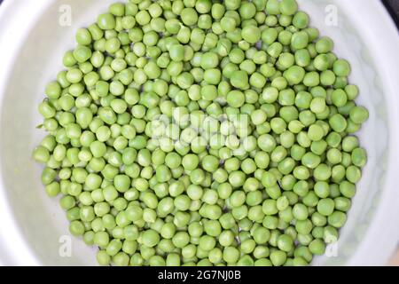 ROHE Erbsen in kleiner weißer Schüssel, auf dem Tisch. Nahaufnahme. Stockfoto