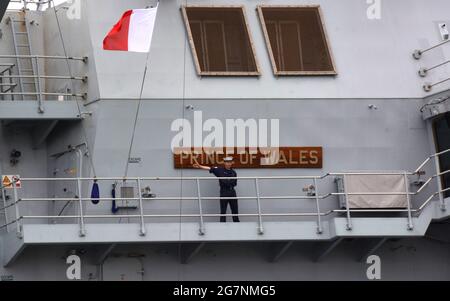 Ein Seemann winkt zu den Seeleute der Royal Navy, der Flugzeugträgerin HMS Prince of Wales, während er nach einer Ausbildung im Mittelmeer und seinem ersten Hafenanschluß außerhalb des Vereinigten Königreichs nach Gibraltar zum Marinestützpunkt Portsmouth zurückkehrt. Bilddatum: Donnerstag, 15. Juli 2021. Stockfoto