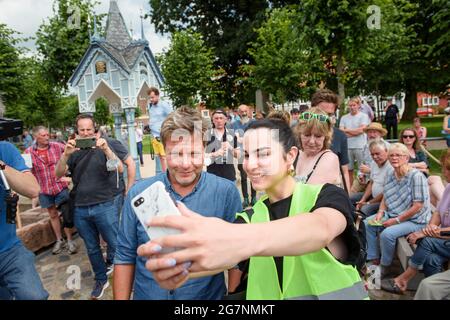 Friedrichstadt, Deutschland. Juli 2021. Robert Habeck, Co-Vorsitzender des Bündnisses 90/die Grünen, macht vor dem Beginn eines Wahlkampfes im Rahmen seiner "Küstenreise" durch Schleswig-Holstein mit einem Bürger auf dem Friedrichstädter Marktplatz eine Talfahrt. Quelle: Gregor Fischer/dpa/Alamy Live News Stockfoto