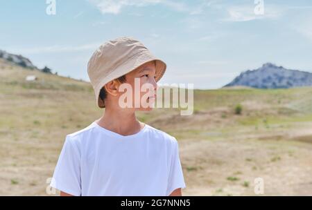 Halblanges Porträt eines asiatischen Jungen im weißen T-Shirt, vor dem Hintergrund der Natur. Stockfoto