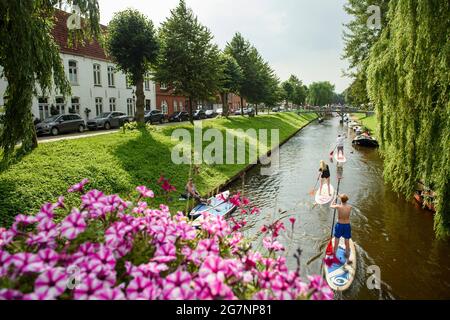 Friedrichstadt, Deutschland. Juli 2021. Drei Stand-up-Paddler reiten bei sonnigem Wetter durch einen Kanal in Friedrichstadt. Quelle: Gregor Fischer/dpa/Alamy Live News Stockfoto