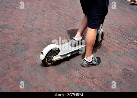 Ein Mann fährt mit seinem Elektroroller auf einer Backsteinstraße in Santa Fe, New Mexico. Stockfoto