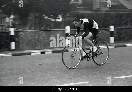 In den 1950er Jahren, historisch, mit dem Kopf nach unten, ein Amateur-Radler in Radbekleidung der damaligen Zeit, der an einem Zeitfahrereignis auf einer städtischen, öffentlichen Straße, Essex, England, Großbritannien, teilnahm. Es ist zu sehen, dass er ein Fahrrad mit festem Gang oder festem Rad fährt, mit einer Bremse nur am Vorderrad und der obligatorischen Glocke am Vorbau. Stockfoto