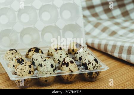 Plastikbox mit 12 Wachteleiern auf Holzsockel. Stockfoto