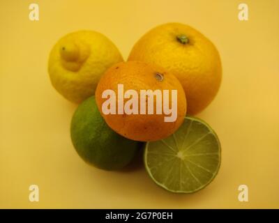 Orange, Zitrone, Limette und Mandarine auf einem gelben Tisch Stockfoto