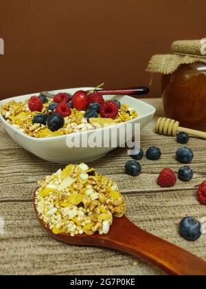 Hochgedrehte Aufnahme einer Schüssel mit frischem und köstlichem Müsli und einem großen Holzlöffel auf dem Tisch Stockfoto
