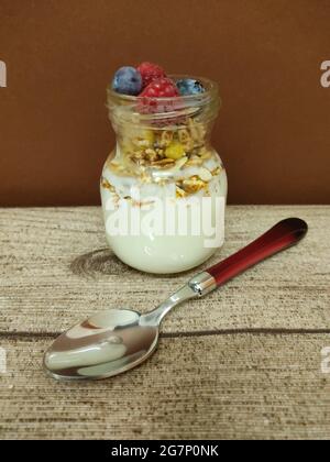 Hochgedrehter Schuss einer Schüssel mit frischem und köstlichem Müsli und einem großen Löffel auf einem Holztisch Stockfoto