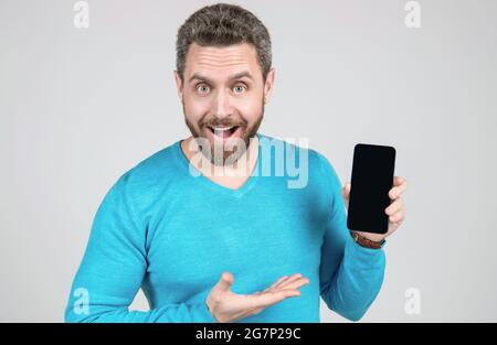 Glücklicher Mann mit Bart demonstriert Smartphone, Förderung Stockfoto