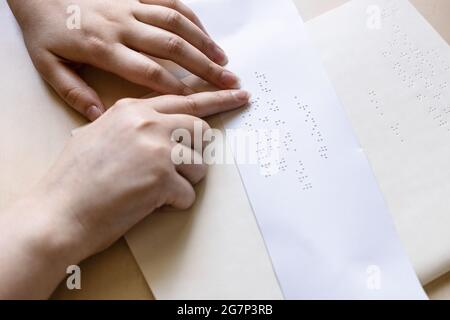 Blinde Frau liest die Notiz in Braille auf einem Blatt Papier aus nächster Nähe Stockfoto