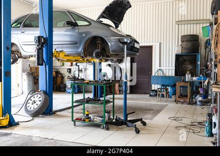 Altes Auto wird in der Autowerkstatt mit einem hydraulischen Lift angehoben Stockfoto