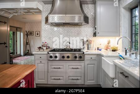 Küchenbereich mit Herd, Dunstabzugshaube, Waschbecken und Schränken in einer Renovierung. Stockfoto