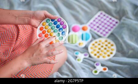 Teenager Mädchen spielt mit Anti-Stress mehrfarbigen Spielzeug popit und einfache Grübchen im Park an einem Sommertag. Stockfoto