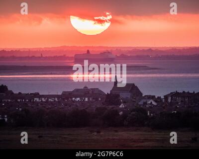 Minster on Sea, Kent, Großbritannien. Juli 2021. UK Wetter: Sonnenuntergang von Minster on Sea, Kent mit Blick auf die Stadt Sheerness (Vordergrund) und wo die Themse (obere Mitte) auf den Medway (untere Mitte) trifft, der von der Isle of Grain getrennt ist. Kredit: James Bell/Alamy Live Nachrichten Stockfoto