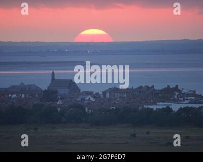 Minster on Sea, Kent, Großbritannien. Juli 2021. UK Wetter: Sonnenuntergang von Minster on Sea, Kent mit Blick auf die Stadt Sheerness (Vordergrund) und wo die Themse (obere Mitte) auf den Medway (untere Mitte) trifft, der von der Isle of Grain getrennt ist. Kredit: James Bell/Alamy Live Nachrichten Stockfoto