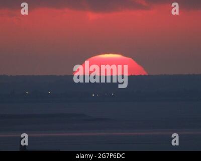 Minster on Sea, Kent, Großbritannien. Juli 2021. UK Wetter: Sonnenuntergang von Minster on Sea, Kent. Ein Funkmast in Essex silhouetted innerhalb der untergehenden Sonne. Kredit: James Bell/Alamy Live Nachrichten Stockfoto