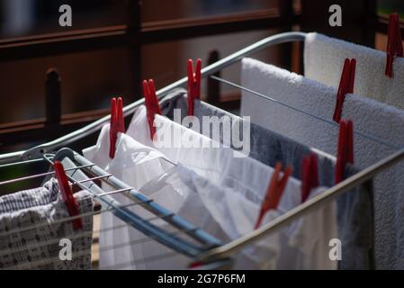 Nahaufnahme von ausgebreiteten Kleidungsstücken auf Faltkleidern in Innenräumen mit roten Schließnadeln Stockfoto