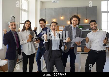 Glückliches, triumrigreichstes Geschäftsteam, das die erfolgreiche Präsentation in einem Arbeitsmeeting feiert Stockfoto