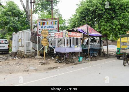Straßenverkäufer auf der Straße mit einem Schild für eine Vorschule in einem armen Teil von Agra, mit dem Taj Mahal gleich um die Ecke. Stockfoto