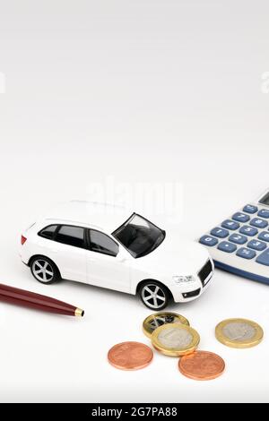 Ein weißes Auto auf weißem Hintergrund mit Euro-Münzen und Rechner. Stockfoto