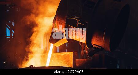 Geschmolzenes Metall, das aus einem großen Schöpfkeller gießt. Gussverfahren.Metallurgische Anlage. Stahlwerk. Stockfoto