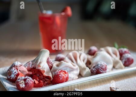 Süsse Knödel oder Khinkali mit Erdbeere und kalter roter Limonade auf dem Tisch Stockfoto