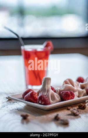 Süsse Knödel oder Khinkali mit Erdbeere und kalter roter Limonade auf dem Tisch Stockfoto