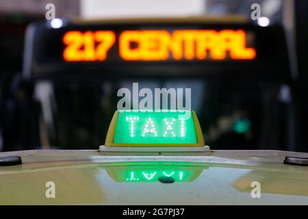 Nächtliches Taxistand auf dem Fahrzeug beleuchtet. City-Ampeln mit Neonfarbe im Hintergrund. Stockfoto