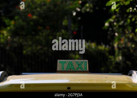 Nächtliches Taxistand auf dem Fahrzeug beleuchtet. City-Ampeln mit Neonfarbe im Hintergrund. Stockfoto