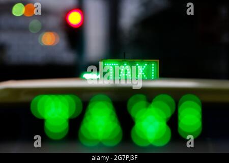 Nächtliches Taxistand auf dem Fahrzeug beleuchtet. City-Ampeln mit Neonfarbe im Hintergrund. Stockfoto