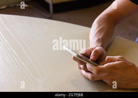 Nahaufnahme der Hände eines Mannes, der das Mobiltelefon auf den Tisch nahm und SMS-Nachrichten annahm. Social Media, Online-Chat, mobile Kommunikationskonzepte Stockfoto