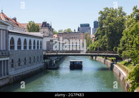 Bild der Mesarski most Brücke in Ljubljana, Slowenien, mit einem Boot, das im Sommer am fluss ljubljanica vorbeifährt. Stockfoto