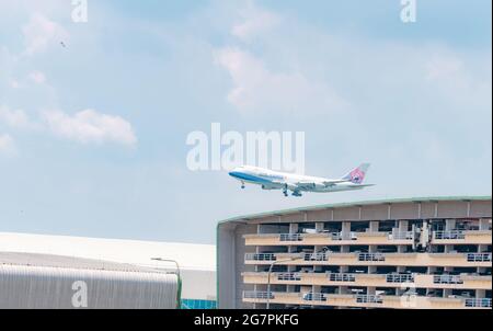 SAMUT PRAKAN, THAILAND-15. MAI 2021 : China Airlines Frachtflugzeug fliegt über dem mehrstöckigen Parkhaus des Flughafens Suvarnabhumi in Thailand. Stockfoto