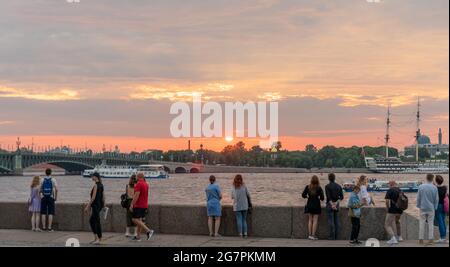 Touristen genießen den Sonnenuntergang während der weißen Nächte auf dem Kutusov-Damm, St. Petersburg, Russland Stockfoto