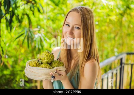 Cherimoya in einer wiederverwendbaren Tasche in weiblichen Händen. Null-Abfall-Konzept, plastikfreies Konzept. Gesunde, saubere Ernährung und Entgiftung. Sommerfrüchte Stockfoto