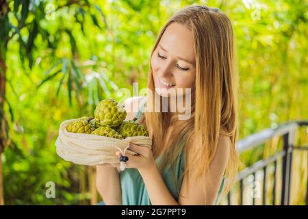 Cherimoya in einer wiederverwendbaren Tasche in weiblichen Händen. Null-Abfall-Konzept, plastikfreies Konzept. Gesunde, saubere Ernährung und Entgiftung. Sommerfrüchte Stockfoto