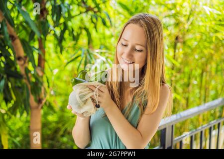 Avocado in einer wiederverwendbaren Tasche in weiblichen Händen. Null-Abfall-Konzept, plastikfreies Konzept. Gesunde, saubere Ernährung und Entgiftung. Sommerfrüchte Stockfoto