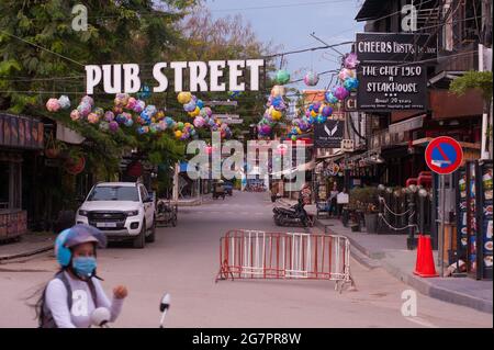 Eine kambodschanische Frau, in einer schützenden Gesichtsmaske/Verkleidung, fährt mit ihrem Motorrad an einer leeren Pub Street vorbei. Alle Bars und Restaurants auf der Pub Street sind seit über 2 Monaten geschlossen. Normalerweise ist die Pub Street mit internationalen Touristen besetzt und ist während der Coronavirus-Pandemie, Siem Reap, Kambodscha, verlassen. Mai 2020. © Kraig Lieb. Stockfoto