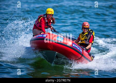 Prerow, Deutschland. Juli 2021. Die Rettungsschwimmer Jasmin Luciani (r) und Pauline Geipel vom DLRG-Wasserrettungsteam segeln in einem aufblasbaren Boot über die Ostsee während einer Rettungsübung neben dem Pier. Rettungsschwimmer sorgen für die Sicherheit der Urlauber an der Ostseeküste. In Mecklenburg-Vorpommern ist die Zahl der Badeunfälle im Vergleich zum Vorjahr in diesem Sommer erneut gestiegen. Bereits seit Juni haben zehn Menschen an der Ostseeküste und an den Binnenseen ihr Leben verloren, während sie im kühlen Wasser baden. Quelle: Jens Büttner/dpa-Zentralbild/dpa/Alamy Live News Stockfoto