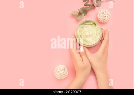 Frau hält Glas mit Creme und grünen Blättern. Frau hält Glas der natürlichen Creme, Nahaufnahme. Glas der Anti-Aging-Creme ist in den Händen Frau mit einem gehalten Stockfoto