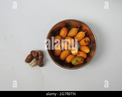 Teller mit rohen Zeidi-Datteln und Samen isoliert auf weißem Hintergrund Stockfoto