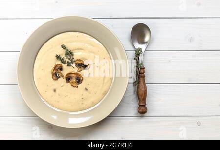 Teller mit köstlicher Pilzsahnesuppe mit Thymian auf dem Holztisch. Horizontale Draufsicht von oben, Kopierbereich Stockfoto