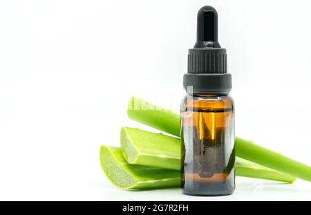 Aloe Vera ätherisches Öl oder Serum mit in Scheiben geschnittener Aloe Vera. Isoliertes Bild auf weißem Hintergrund. Leerraum auf der Flasche mit der hellbraunen Farbe für Etikett d Stockfoto