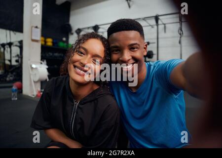 Gemischte Rennfreunde, die gemeinsam im Fitnessstudio ein Foto machen. Glücklicher afroamerikanischer Mann und Frau, die ein Selfie machen. Hochwertige Fotos Stockfoto