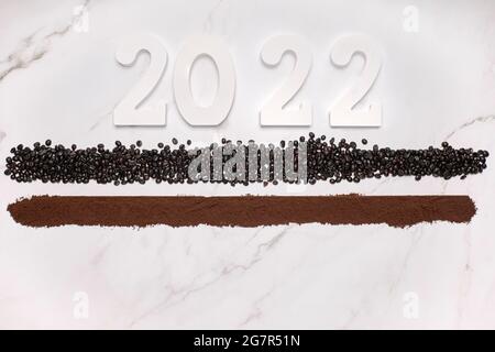 Holznummer 2022 auf einer Linie von gemahlenem Kaffee und einer Linie von Kaffeebohnen. Konzept für Neujahrs- und Weihnachtsfeiern Stockfoto
