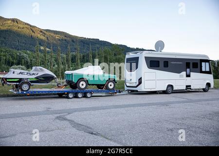 Sehr großer, teurer und luxuriöser Wohnwagen mit Wohnwagen und Jet-Ski und Jeep auf einem Parkplatz in Österreich Stockfoto