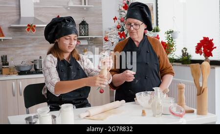 Großmutter lehrt Enkelin, wie bereiten köstliche Xmas Lebkuchen Dessert machen Cookies Teig mit Nudelholz. Glückliche Familie genießen Kochen Feier weihnachten Urlaub Stockfoto