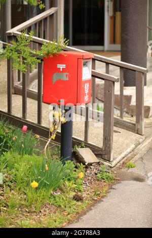 Roter japanischer Briefkasten auf der Wegseite am See Inawashiro Stockfoto