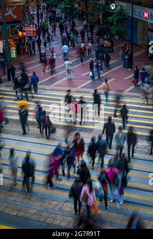 Fußgänger überqueren die Straßenbahnschienen in Causeway Bay, Hong Kong Island, mit Unschärfe-Effekt durch langsame Verschlusszeit Stockfoto